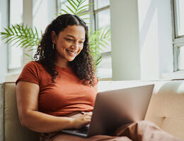 A woman on a couch uses a laptop.
