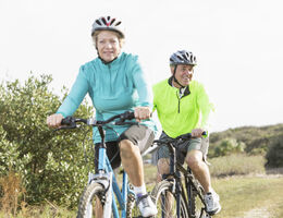 A woman and a man ride bikes off-road.