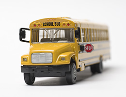 A yellow toy school bus with its stop sign extended, all on a white background. 