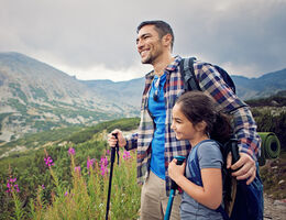 A father and daughter smile as they hike.