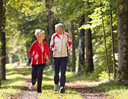 An older man and woman jog through a park.