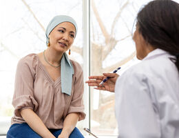 A doctor talks to a woman who is wearing a head covering for patients with cancer-related hair loss. 
