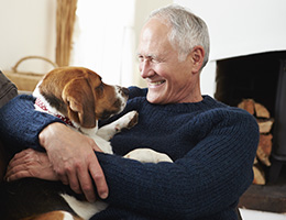 Smiling man cuddling with pet dog in a home setting.